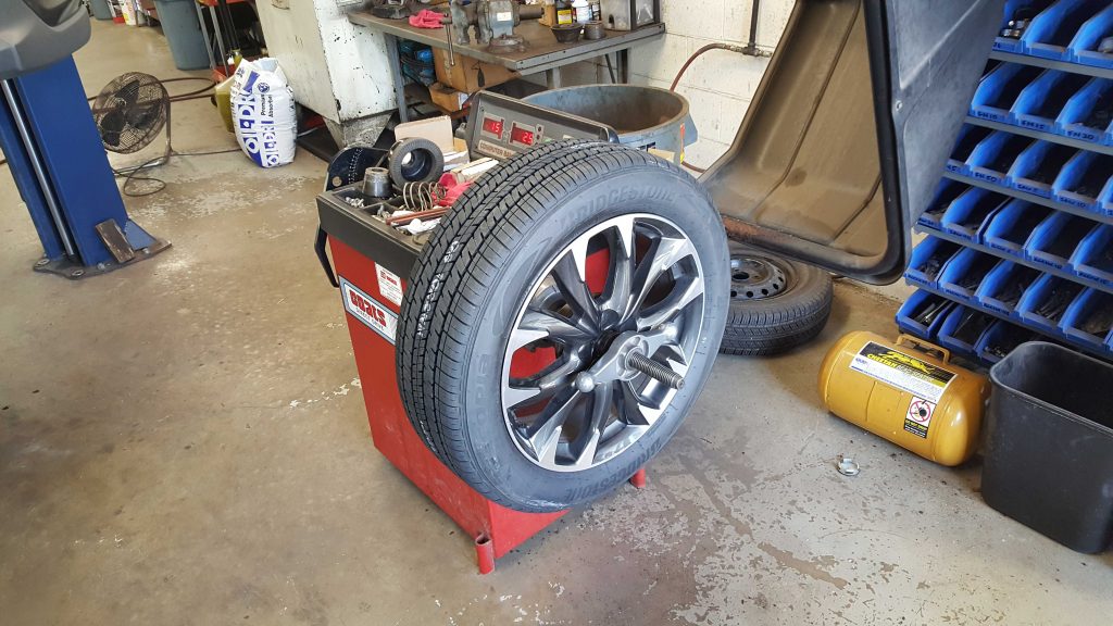 Car tire being repaired in a garage, with various equipment visible in the background