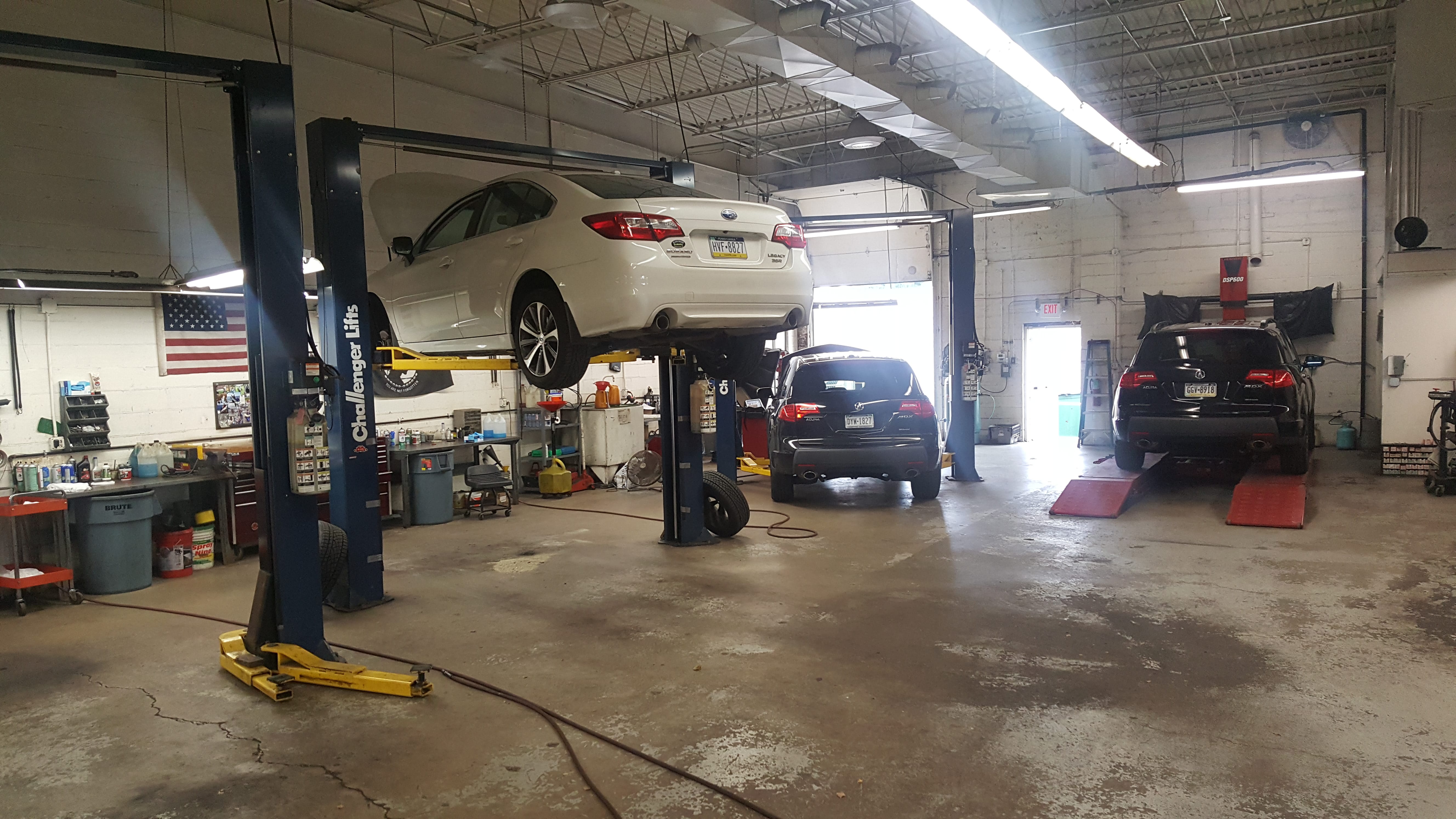 Three cars undergoing maintenance in a garage, with two of them positioned on ramps for easier access