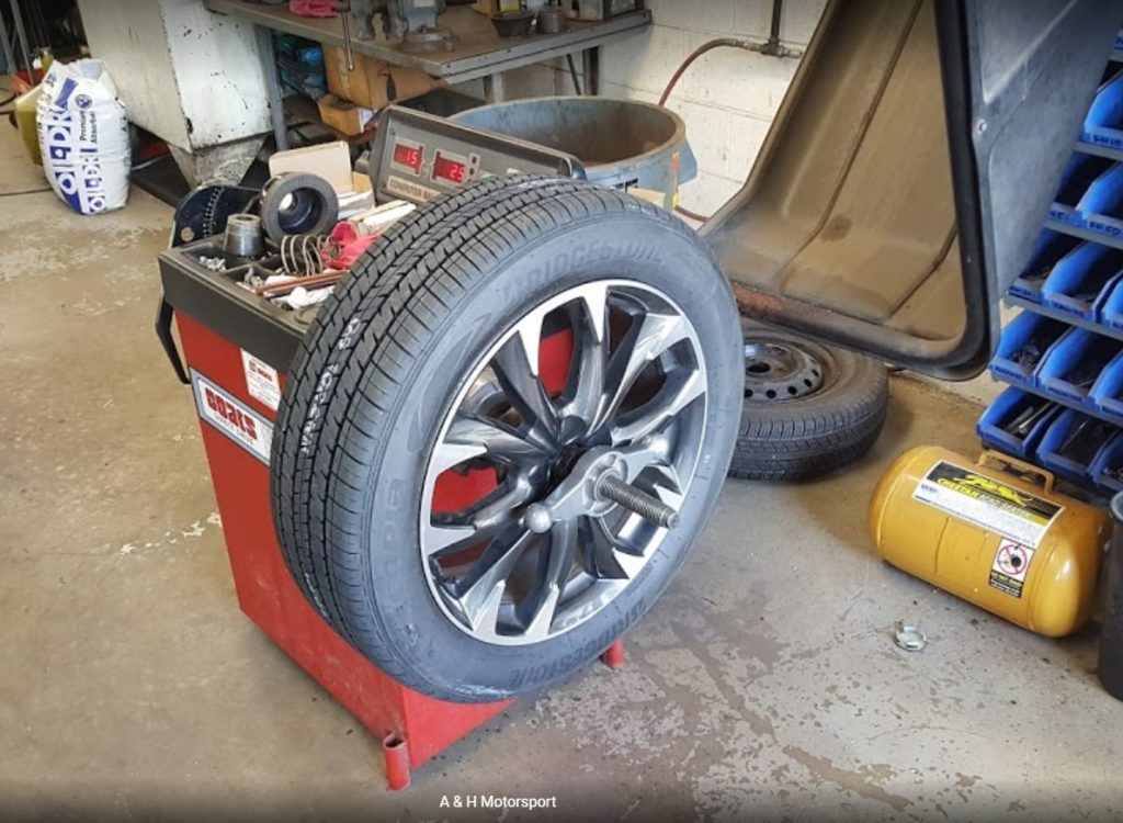 A car tire being serviced inside a garage, with tools and equipment nearby, highlighting the importance of regular maintenance