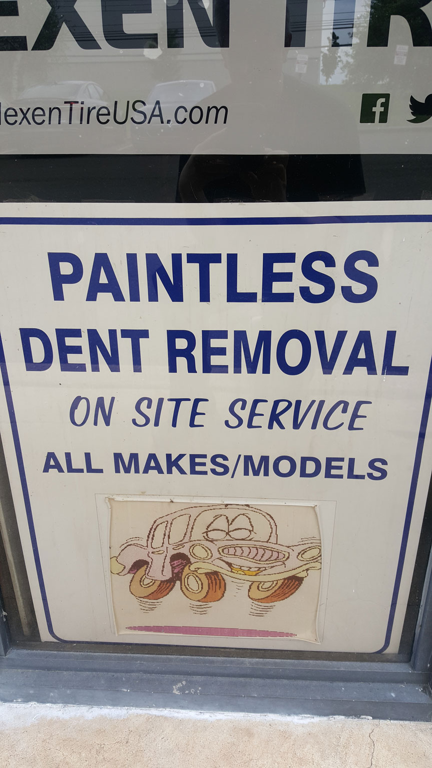 A poster advertising Paintless Dent Removal, affixed to a glass door, promoting the service offered