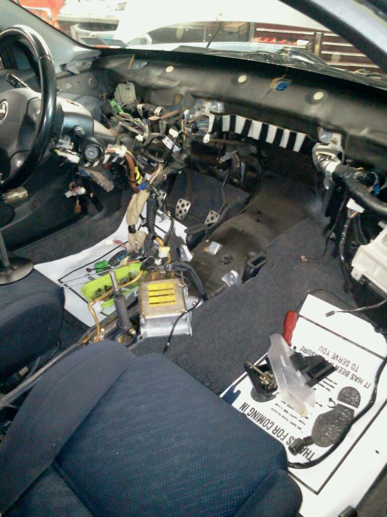 A close-up view of the car's messy engine bay, showing Aguilar parts scattered around, indicating maintenance or repair work in progress