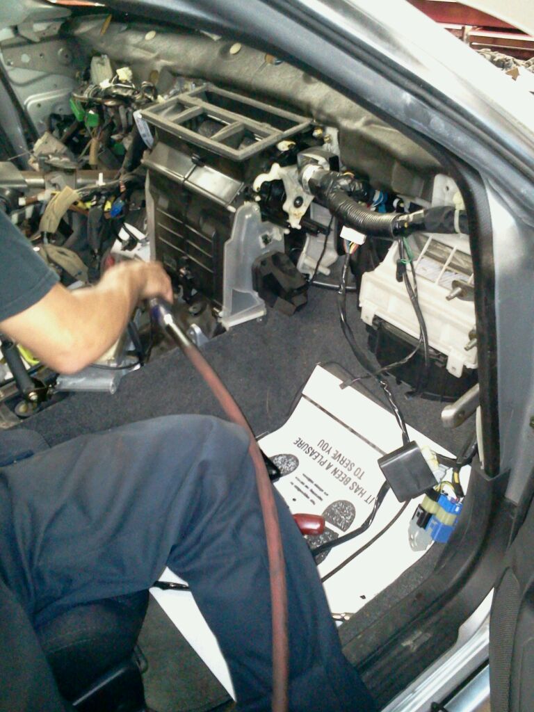 A mechanic performing repairs on the car's front end, using specialized tools and equipment